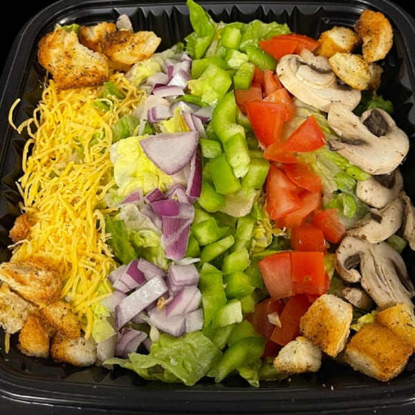 A vibrant salad with lettuce, red onions, green peppers, tomatoes, mushrooms, shredded cheese, and croutons.